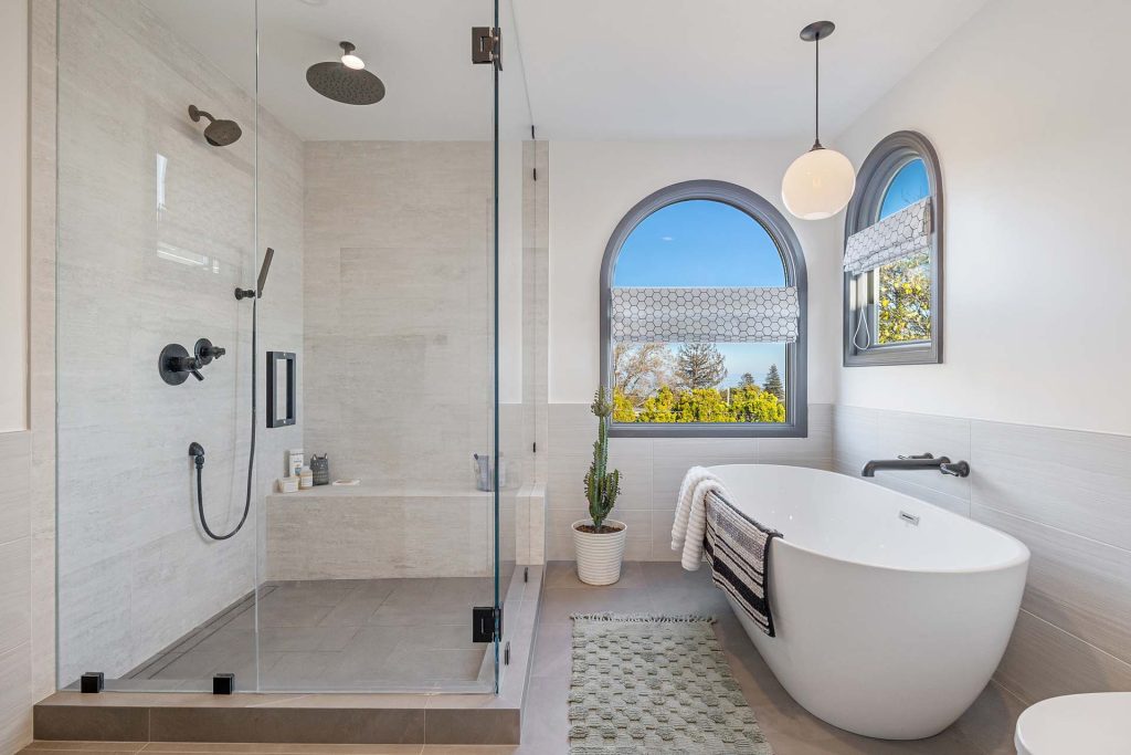 evoke-interior-designs-san-francisco-ca-should-you-renovate-or-redecorate-your-home-renovated-bathroom-frameless-shower-soaking-tub-neutral-colors-arched-window-creative-residential-design